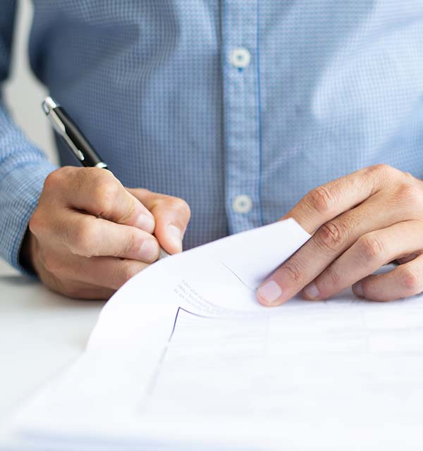 Hombre firmando un documento sobre un escritorio